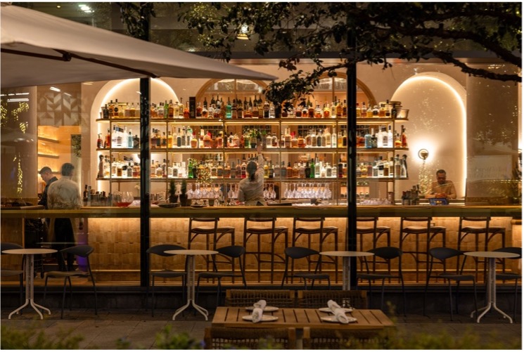 Illuminated bar with bartenders and empty stools, showcasing a part of Tampa’s vibrant nightlife at Predalina.