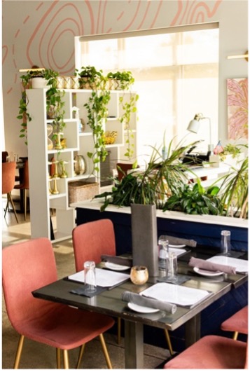 Rome & Fig’s dining room featuring a dark table with four pink chairs.